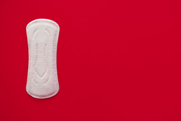 One menstrual pad on a red background, top view, place for text, blood-absorbing agent for women, critical days, medical pads