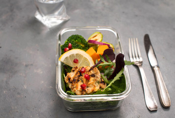 Healthy lunch box container  with grilled chicken meatballs, broccoli, zucchini, pumpkin and salad on grey background selective focus.