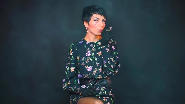 Portrait of dominant woman smoking cannabis from a pipe.