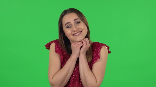 Portrait of tender girl in red dress is saying wow with shocked facial expression. Green screen