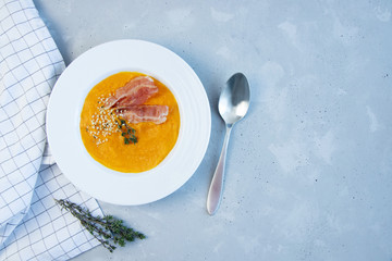 Pumpkin puree soup with bacon on a gray background. Copy space