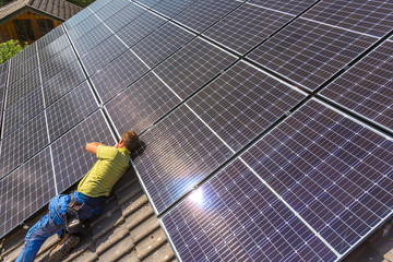 Installing solar photovoltaic panel system. Solar panel technician installing solar panels on roof....