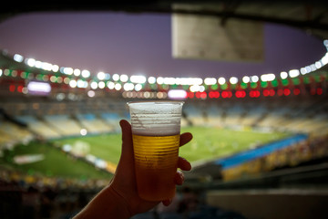 Disposable glass with beer. Soccer stadium on the background © 9parusnikov