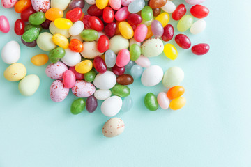 Happy Easter concept. Preparation for holiday. Easter candy chocolate eggs and jellybean sweets isolated on trendy pastel blue background. Simple minimalism flat lay top view copy space.