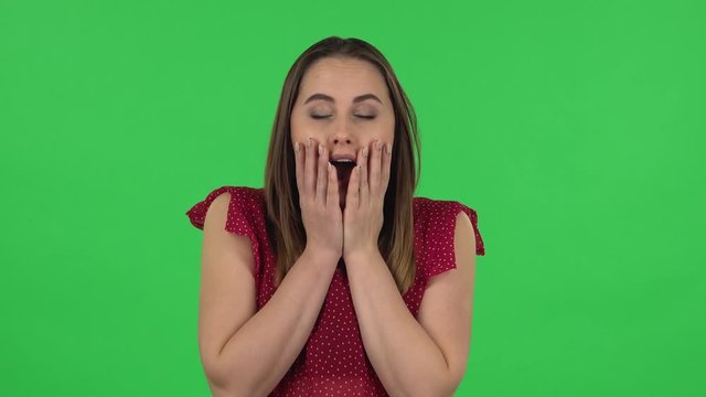 Portrait of tender girl in red dress is frustrated saying oh my god and being shocked. Green screen