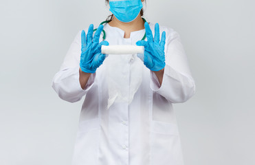 medic woman in white coat and mask holds a twisted gauze bandage for dressing wounds