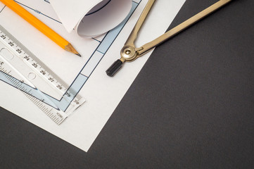 Rolled house diagrams and accessories for drawing lying on construction drawing on a black background