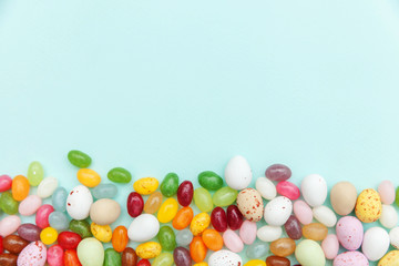 Happy Easter concept. Preparation for holiday. Easter candy chocolate eggs and jellybean sweets isolated on trendy pastel blue background. Simple minimalism flat lay top view copy space.