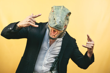 Senior man wearing t-rex dinosaur mask - Crazy hipster guy having fun celebrating carnival holidays...