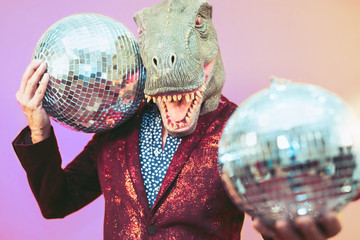 Senior man having fun wearing t-rex mask in discotheque - Elegant dinosaur masquerade male...