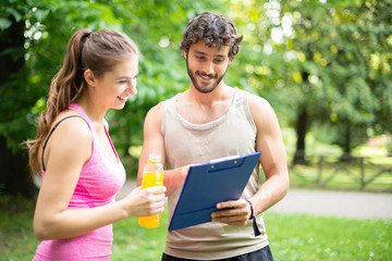 Man showing a training table to a woman, personal training and fitness concept