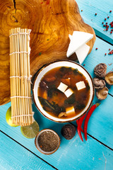 Asian soup with tofu cheese next to vegetables on the table background