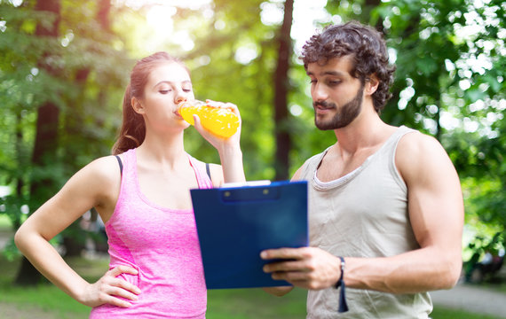 Man showing a training table to a woman, personal training and fitness concept