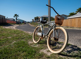 Old rusty bicycle leaning against a street sign post on a sunny day.