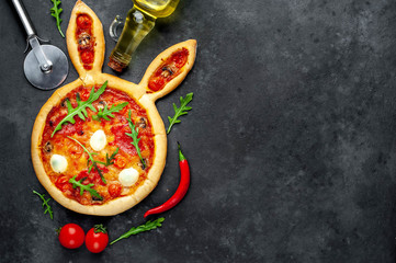 Easter pizza in the form of a hare with eggs, tomatoes, sunflower oil on a stone background with...