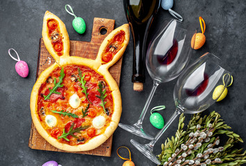 Concept  celebrations  Easter .Holiday Easter pizza in the shape of a rabbit with eggs, a bottle of wine and glasses on a stone background 
