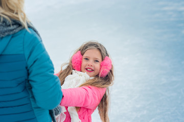 The girl on ice skating in pink wear looking on mum