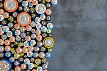 Close up of positive ends of colorful  discharged batteries of different sizes and formats, top view, copy space. Used alkaline battery on black background. Hazardous garbage concept. 