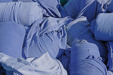 Close-up view of the contents of a big industrial laundry container with rolls of blue textiles 