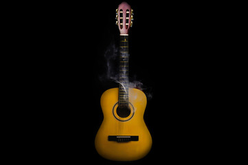 Acoustic guitar in smoke on the black background.. musical instrument. strings on the guitar neck