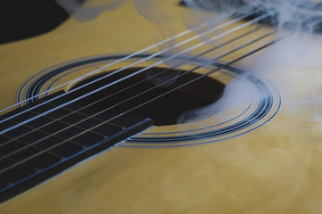Acoustic guitar in smoke close up. musical instrument. strings on the guitar neck