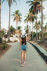 Curly girl in tropics. Skinny figure sexy body, tanned skin, a lot of palm trees, warm photo. relax and having fun on vacation. Outdoor lifestyle back view. Concept time to travel