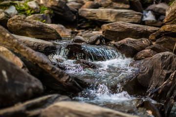 water flows over stones. Beautiful mountain waterfall in the forest. 