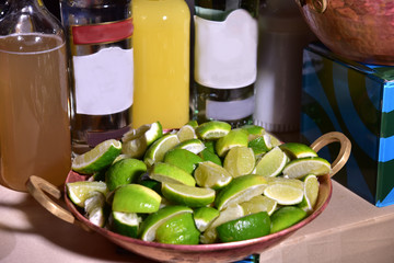 lemons cut into pieces in a copper bowl with some bottles out of focus in the background