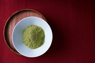 A bowl of the ayurvedic powder Sidr (Zizyphus jujuba) on a deep red background