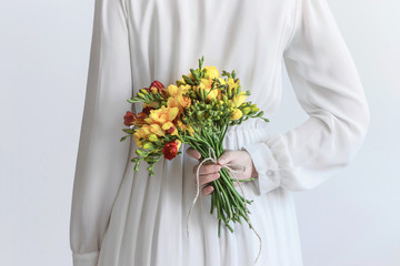 white dress woman holding yellow freesia flower bouquet 