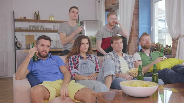 Sad friends watching TV at the boring house party