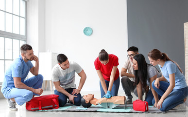 Instructor demonstrating CPR on mannequin at first aid training course - obrazy, fototapety, plakaty