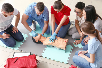 Instructors demonstrating CPR on mannequin at first aid training course - Powered by Adobe