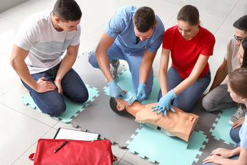 Instructors demonstrating CPR on mannequin at first aid training course