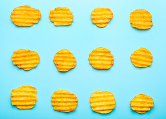 Tasty potato chips on color background