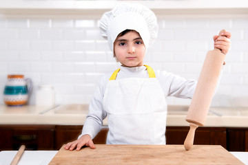 child dressed as a chef with a rolling pin in his hand