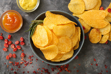Bowl with tasty potato chips on table