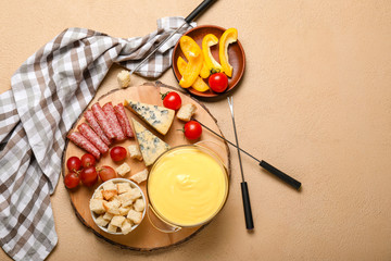 Cheese fondue with snacks on color background