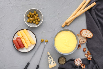 Cheese fondue with snacks on grey background
