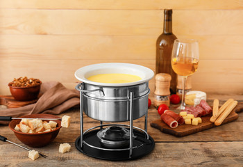 Cheese fondue with snacks and wine on table