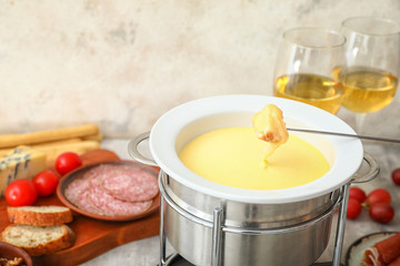 Dipping of crouton into cheese fondue on table