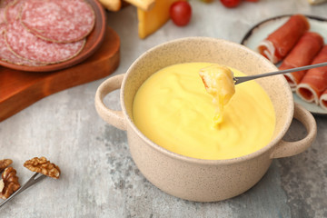 Dipping of crouton into cheese fondue on table
