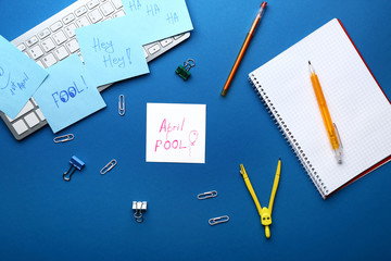 Stationery with computer keyboard on color background. April Fool's Day prank