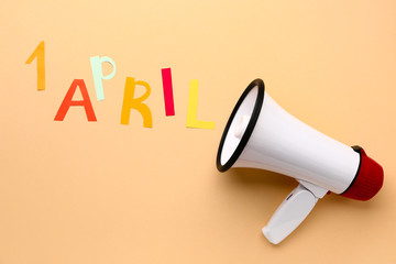 Megaphone on color background. April Fool's Day prank