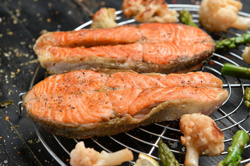 Tasty fried salmon and vegetables on table