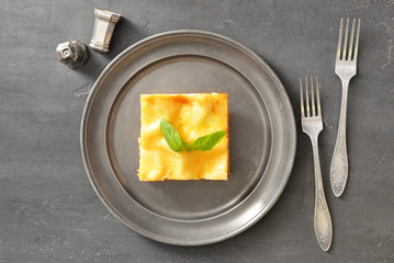 Plate with piece of tasty homemade lasagna on grey background