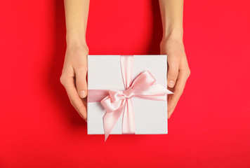 Female hands with beautiful gift box on color background