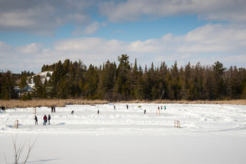 Children skating and playing ice hockey on a frozen pond