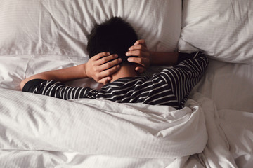Preteen tween boy covering ears with his hands in bed, ADHD, teen Autism,sleep disorder, mental health in children, not want to hear, wake up kid for school concept