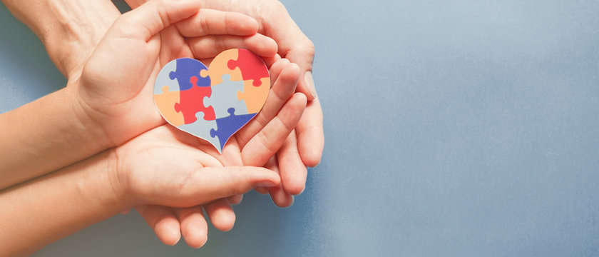 Adult and chiild hands holding jigsaw puzzle heart shape, Autism awareness,Autism spectrum disorder family support concept, World Autism Awareness Day